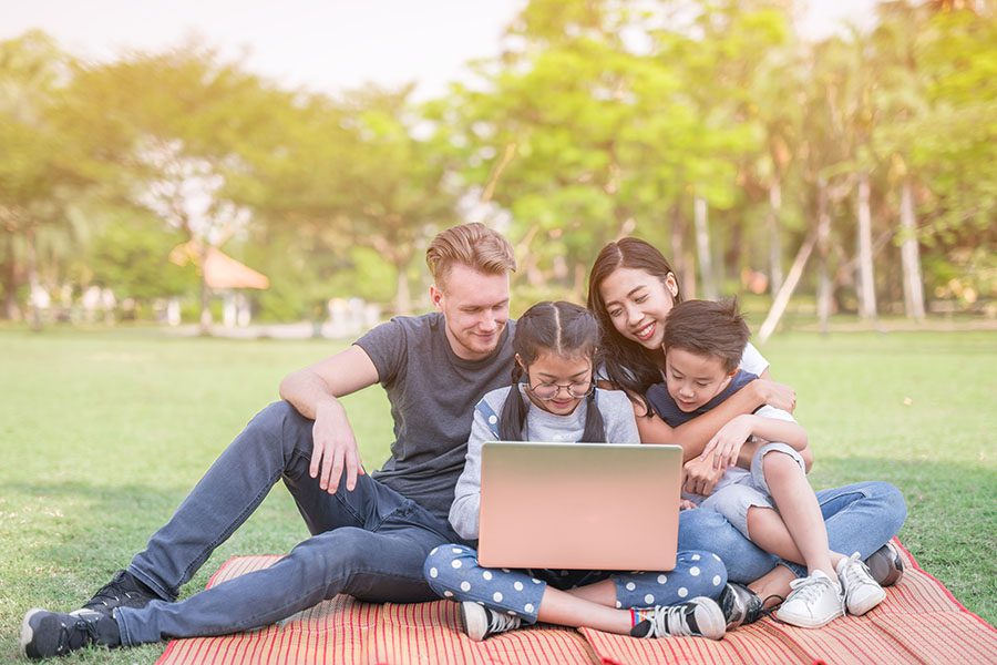 Blog - Family With Kids Sitting In The Park Using Their Laptop