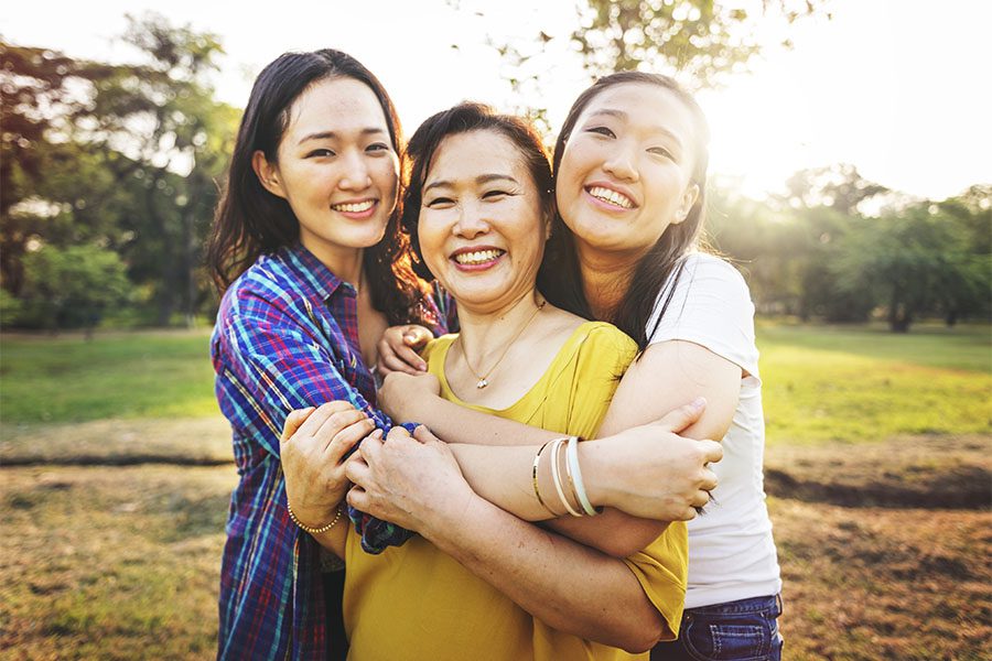 Umbrella Insurance - Two Daughters Hugging Their Mom Outside